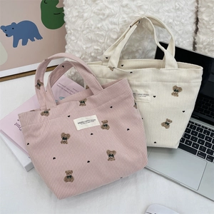 Pink and beige corduroy tote bags with bear embroidery in a cozy workspace setting