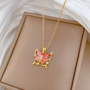 Macro detail of golden butterfly pendant with pink wings and sparkling crystals