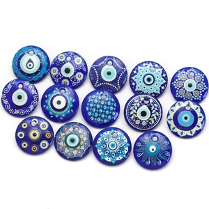 Flat lay of circular Evil Eye glass charms with diverse mandala patterns for DIY jewelry