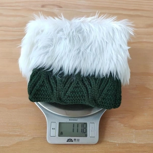 Green knitted Christmas stocking weighing 111.8g with white faux fur trim on a scale