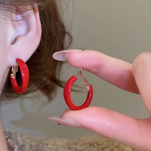 Close-up of a woman wearing vintage red geometric round hoop earrings with gold accents