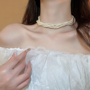 Dettaglio della collana girocollo multistrato di perle finte con design intrecciato su pizzo