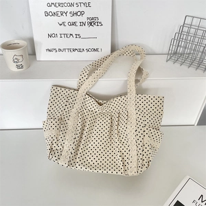Close-up of beige polka dot canvas tote bag featuring delicate lace trim and side pocket