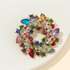 Vintage gold crystal flower wreath brooch with colorful rhinestones on a white stand