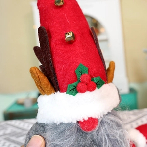 Makroaufnahme von Weihnachtsgnom-Plüsch mit rotem Hut, Geweih und goldener Glocke