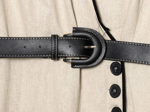 Detail eines beigen Leinenkleids mit schwarzem Kunstleder-Gürtel und Kontrastnähten