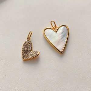 Macro detail of heart-shaped pendant with white shell inlay and gold-plated zircon frame