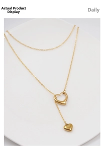 Detail of gold Y-shaped double layer necklace with hollow heart pendant on a white plate