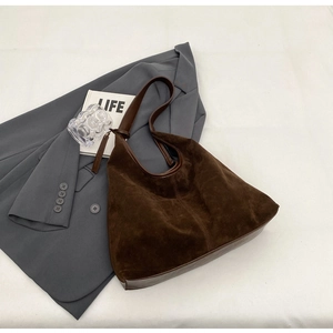 Detailed close-up of dark brown suede and PU leather stitching on a large hobo tote bag