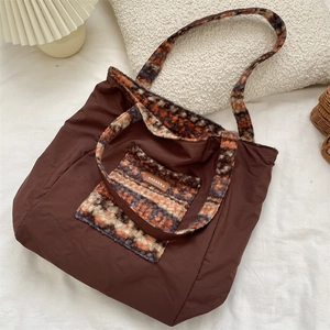Detail of a brown nylon tote bag featuring colorful knit jacquard pockets and strap design