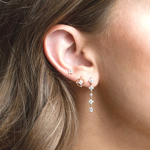 Gold flower stud earrings set with blue zircon and long tassels worn on ear