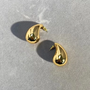 Detailed view of polished 18K gold plated teardrop earrings with a mirror finish surface
