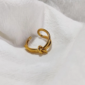 Macro shot of 14K gold plated knot ring with adjustable opening on white fabric
