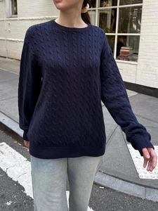 Detail of navy blue cable knit sweater with ribbed crew neck on street model
