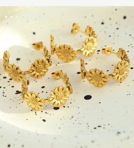Detailed close-up of golden daisy flower hoop earrings with intricate petal texture