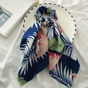 Detail of floral satin ponytail scarf scrunchie with tropical leaf print in a ceramic dish