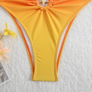 Dettaglio di costume da bagno giallo con stella marina dorata in metallo e tessuto a pieghe