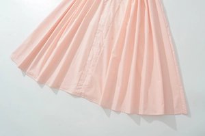 Detailed view of the pleated light pink woven fabric and hem on a vintage summer dress