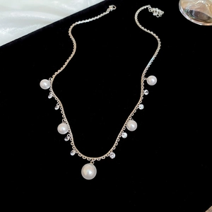 Detail of elegant gold necklace with white pearls and rhinestones on black velvet
