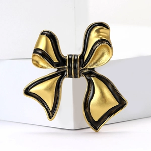 Close-up of elegant gold and black enamel bow brooch with detailed metallic texture