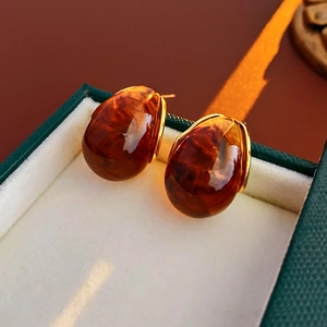 Detailed macro view of amber resin drop earrings in gold frames inside a jewelry box