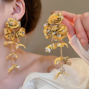 Detailed close-up of yellow chiffon flower tassel earrings worn by a model in a beach style