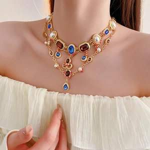 Close-up of vintage gold necklace with colorful gemstones and pearls worn by a model