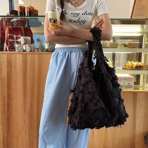Detail of black canvas hobo bag featuring unique tassel fringe texture and large capacity