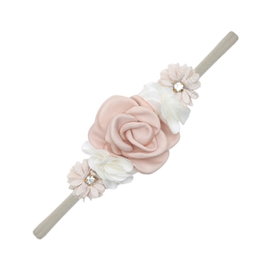 Detail of pink satin roses and crystal accents on a grey nylon baby headband