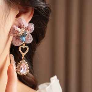 Close-up of vintage pink lace flower earring with crystals and golden heart drop