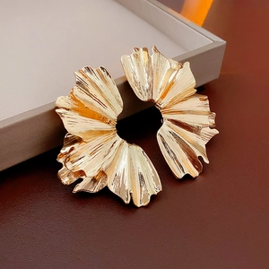 Detailed macro view of gold-tone pleated fan-shaped metal earrings on a jewelry box