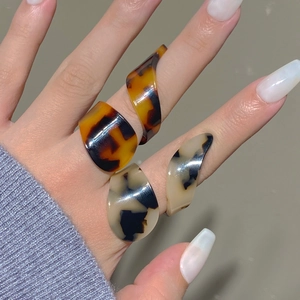 Detail of irregular geometric acrylic rings with brown tortoiseshell patterns on a hand