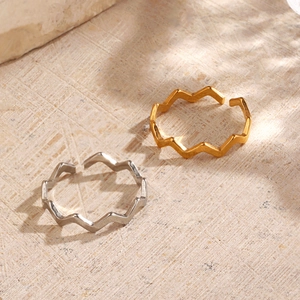 Minimalist 18K gold and silver wavy open rings displayed on a textured stone surface