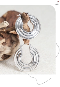Detailed close-up of textured silver hoop earrings with a layered geometric design