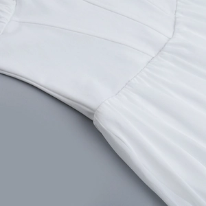 Détail de la robe blanche montrant les coutures précises et le tissu en maille multicouche