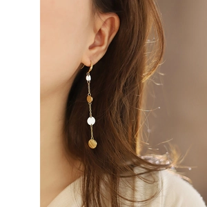 Long tassel drop earrings with gold and silver round discs worn by a model