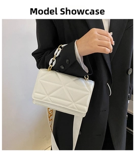 Detail of white quilted mini bag with wide logo strap and gold chain handle on model