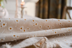 Close-up of beige cotton linen fabric with white and yellow daisy prints for tablecloth