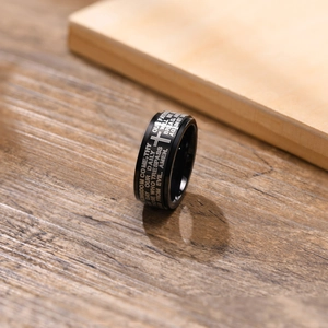 Macro shot of black matte stainless steel ring with religious scripture and cross