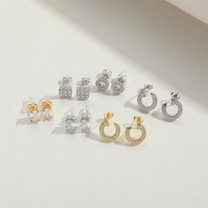 Detailed close-up of gold and silver pave zircon stud earrings and small C-shaped hoops