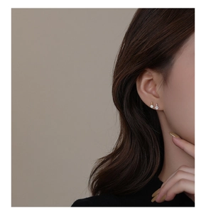 Close-up of minimalist gold and silver stud earrings with sparkling cubic zirconia on model