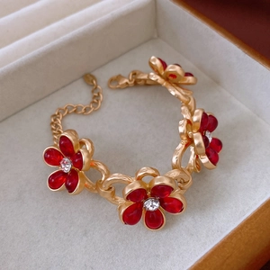 Close-up of golden floral bracelet with red petals and rhinestones in beige jewelry box