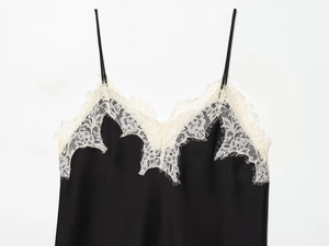 Close-up of black satin camisole featuring delicate white lace trim on the V-neckline
