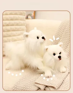 Detail of two white Pomeranian plush toys showing soft fluffy fur on a beige sofa