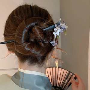Detail of butterfly and purple flower hair stick with gold tassels in a hair bun