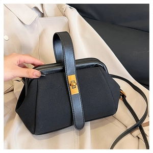 Detail of vintage black suede shell bag with golden lock and leather handle grip