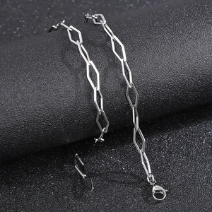 Detailed view of silver geometric hexagonal links with lobster clasp on dark pedestal