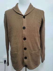 Detail of camel knit cardigan showing button closure and front patch pockets
