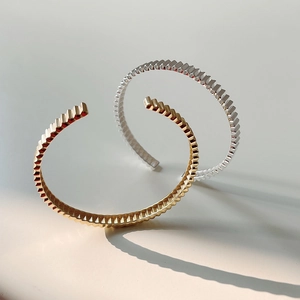 Detail showing gold and silver S925 sterling silver open bangles with gear-like geometric texture