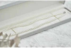 Classic white round pearl necklace presented in a luxury gray jewelry gift box on lace